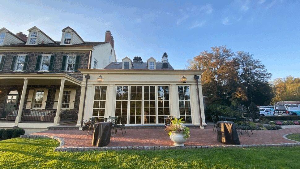 Sunroom with large grid glass doors opening onto a brick patio and lawn