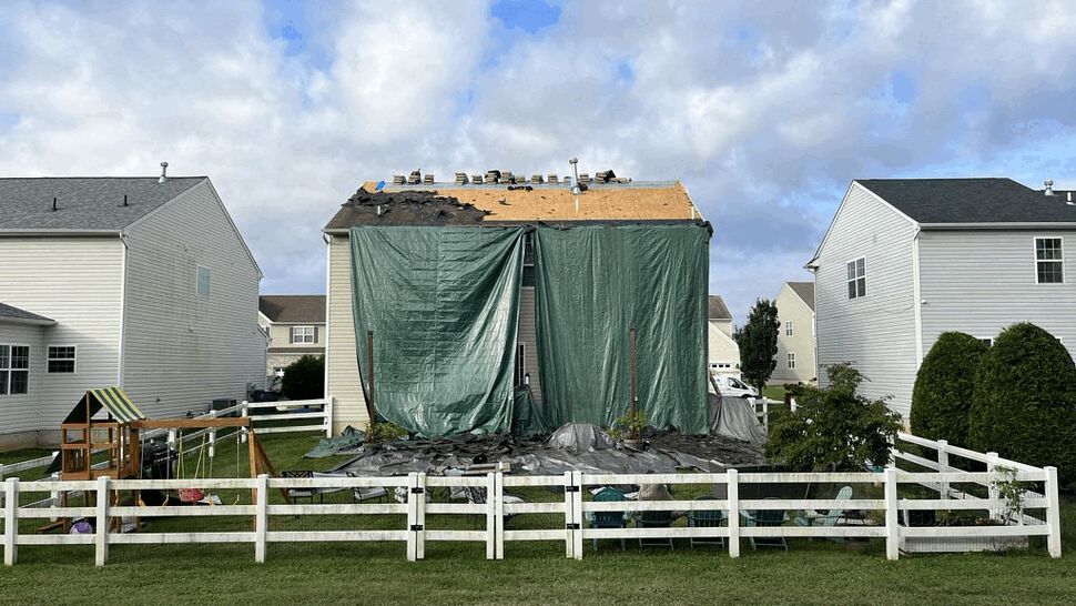 Storm damage protection with tarps | Tycos Roofing And Siding Inc Rear of house covered by large green tarp with roof decking exposed