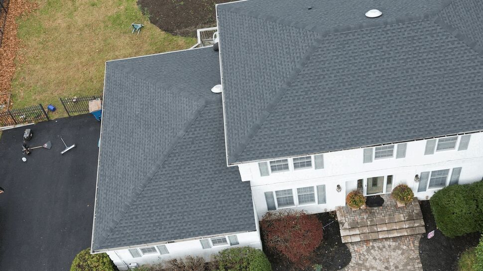 Top-down drone view of the property's hip roof with dark asphalt shingles.