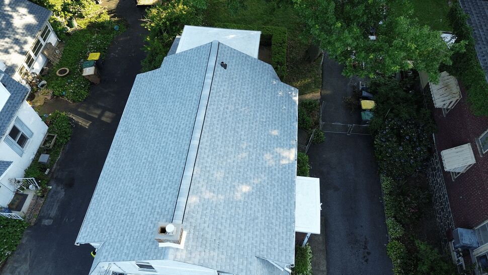 Top-down view of the main shingle roof ridge and chimney on a residential property.