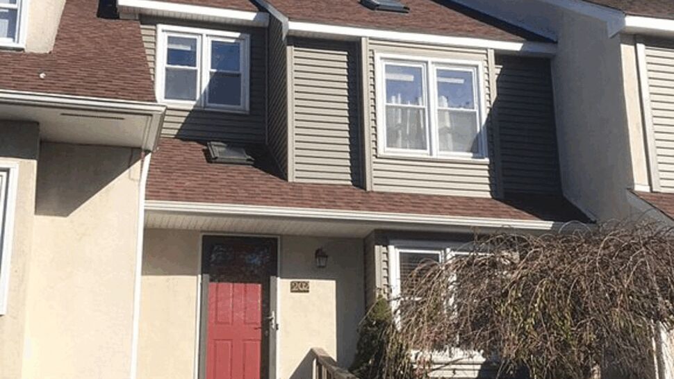 Front townhouse with red door, brown roof shingles and beige siding