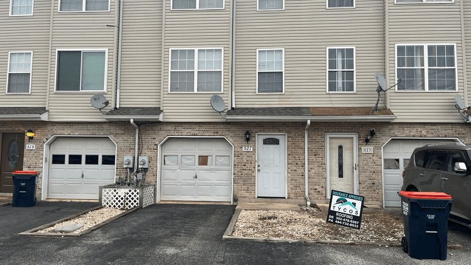 Townhouse front with Tycos sign | Tycos Roofing And Siding Inc Townhouse row with a Tycos Roofing yard sign by the driveway