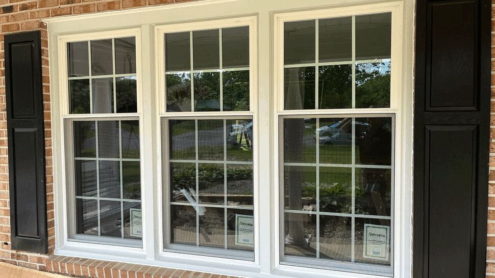 Triple Panel Window Installation | Tycos Roofing And Siding Inc Three white-framed double-hung windows with grid patterns in a brick wall