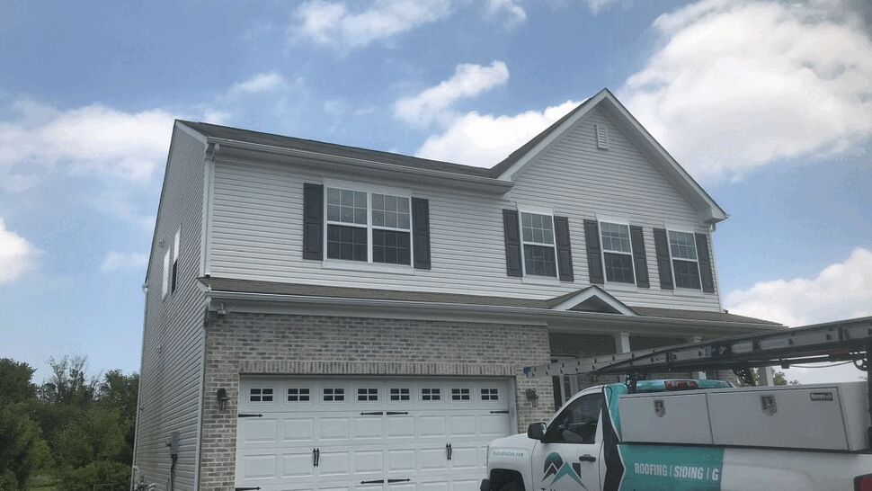 Two-story roof and siding service | Tycos Roofing And Siding Inc Two-story house with Tycos service truck parked in the driveway under a blue sky