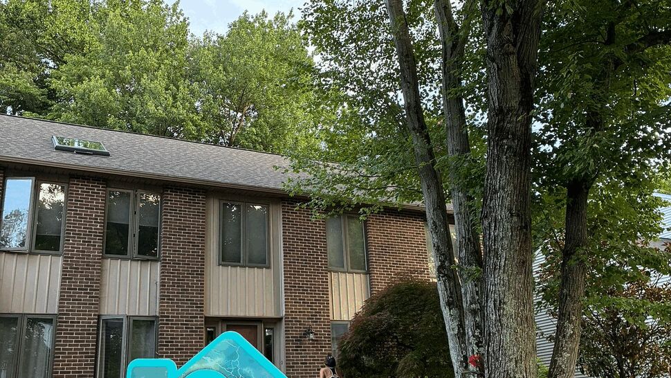 Tycos yard sign near trees in front of a home with vertical siding panels