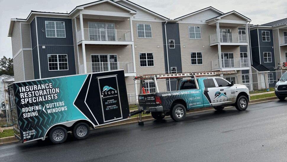 Tycos branded truck and trailer parked in front of a multi-unit building