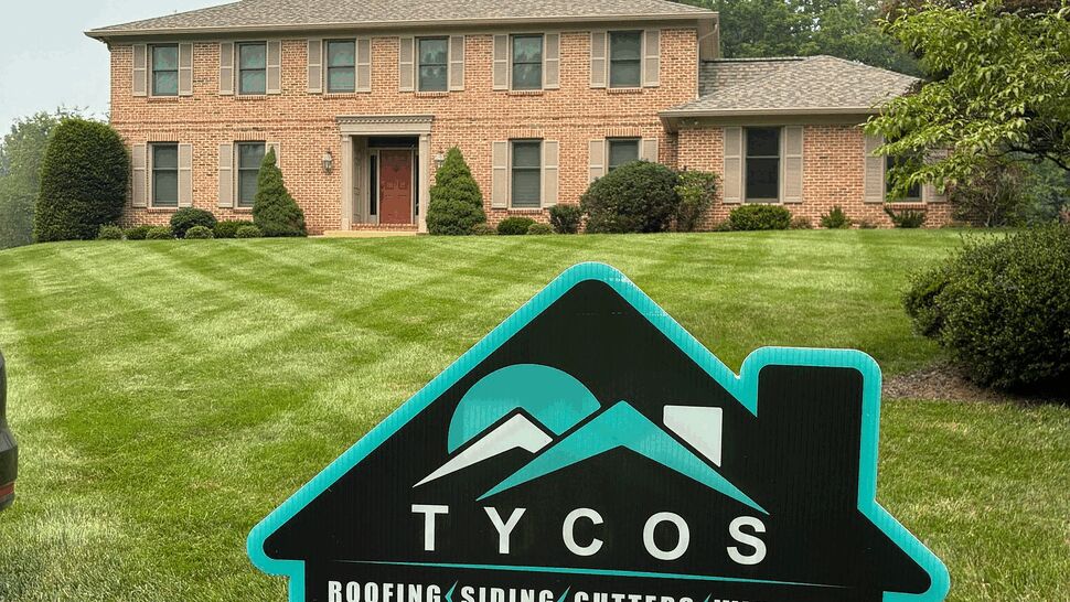 Tycos yard sign on the front lawn of a two-story brick house.