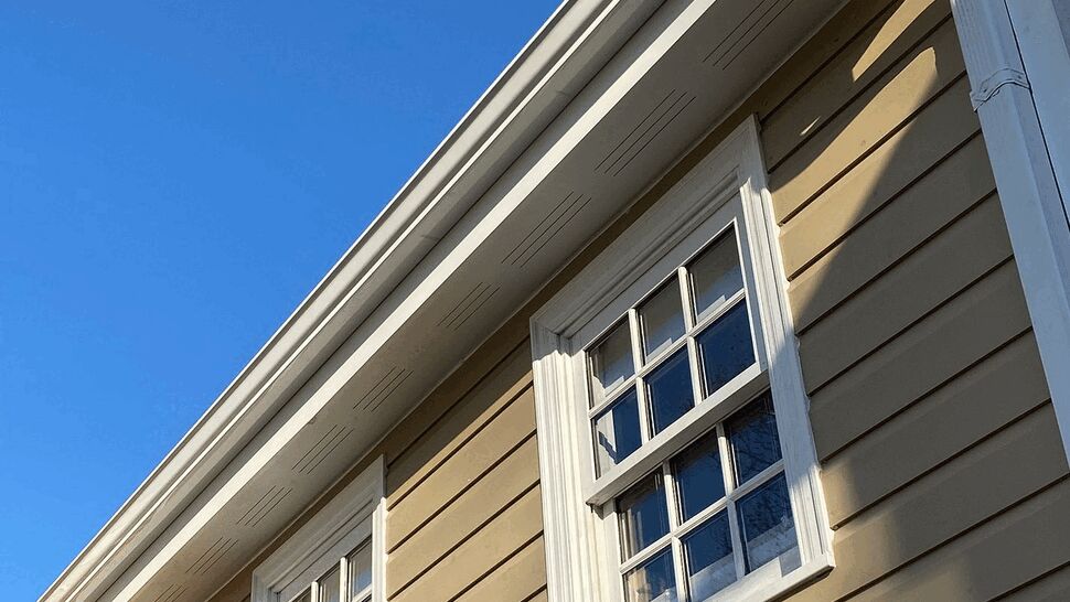Upper double-hung windows with beige siding and white soffit and gutter above.