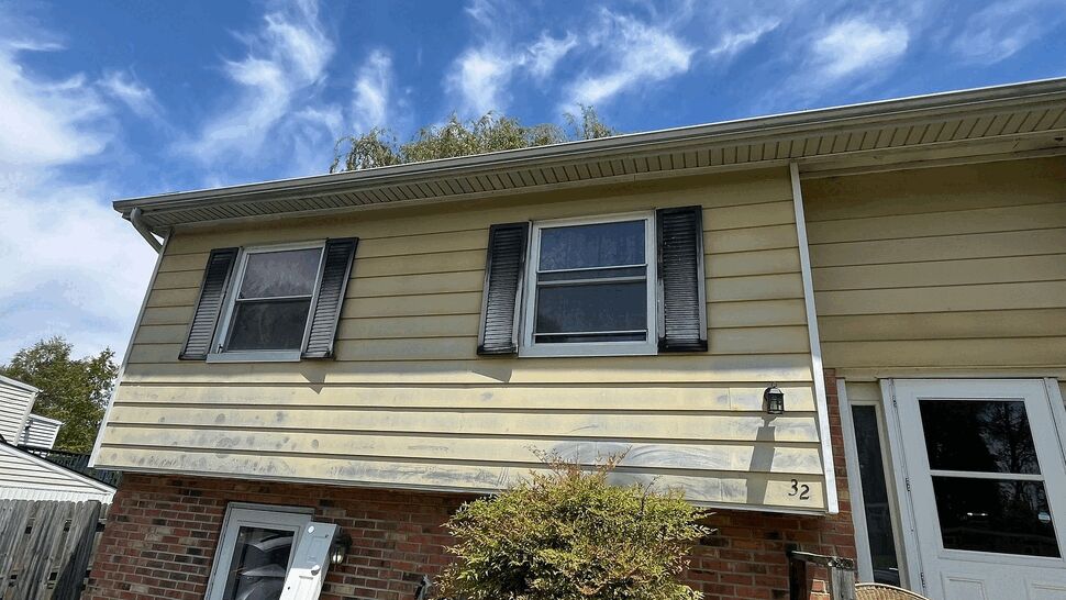 Upper floor windows on yellow siding above a brick lower level