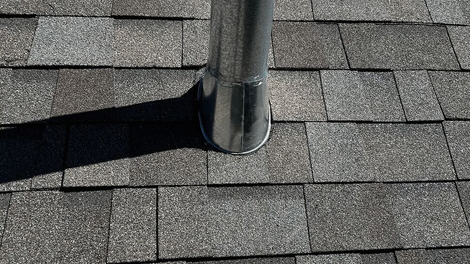 Close-up of metal vent flashing sealed to asphalt shingles