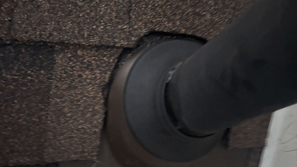 Close-up of vent pipe flashing sealed into brown asphalt shingles