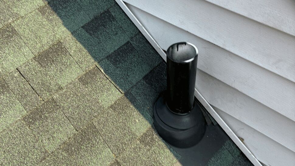 Plumbing vent pipe with rubber boot flashing next to white vinyl siding