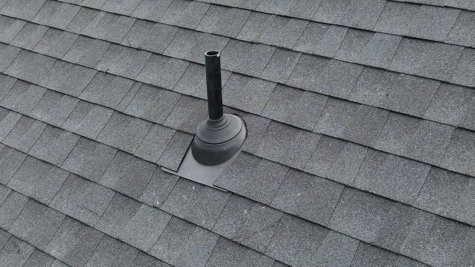Close-up of a roof vent pipe with rubber flashing on asphalt shingles.