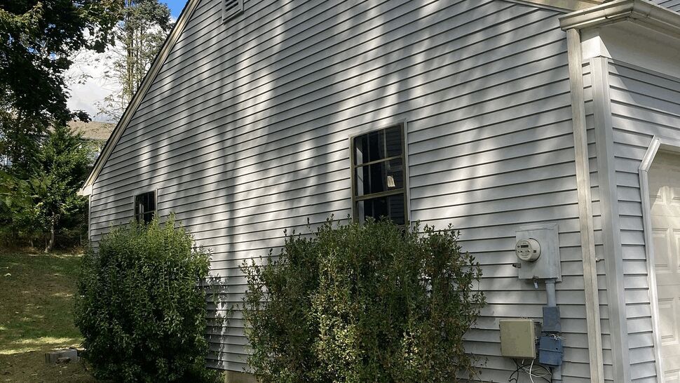 Side of house with white vinyl siding, window, and downspout