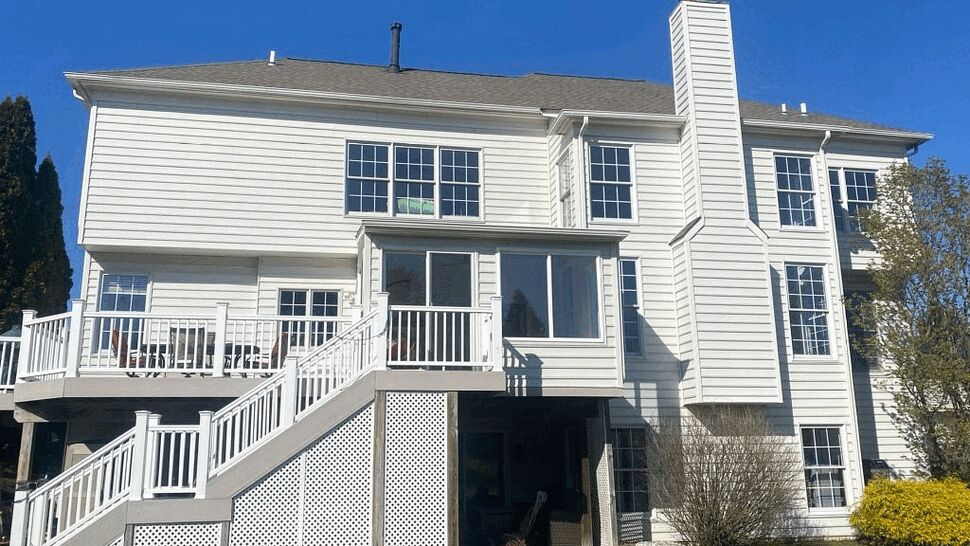 Rear white house with raised deck, stairs, lattice skirting and vinyl siding