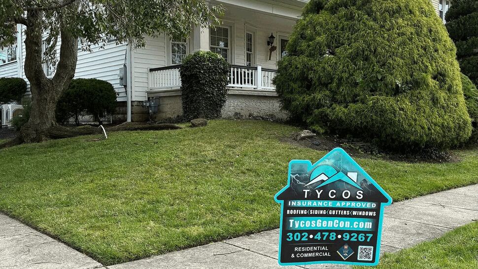 White Home Siding Project | Tycos Roofing And Siding Inc White two-story home with siding and a Tycos Roofing and Siding sign