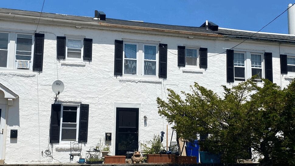 White two-story rowhouse with black shutters, windows and front door