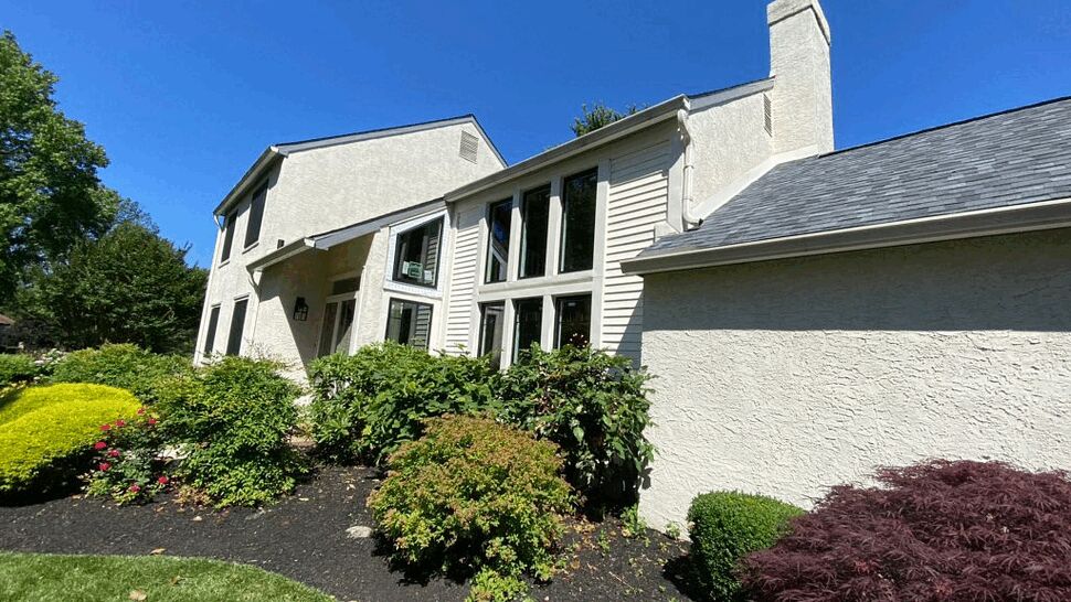 White stucco house exterior with landscaping under a blue sky.