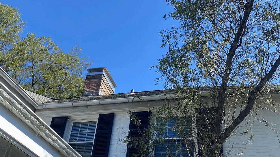 White brick house with glass sunroom and upper windows under blue sky