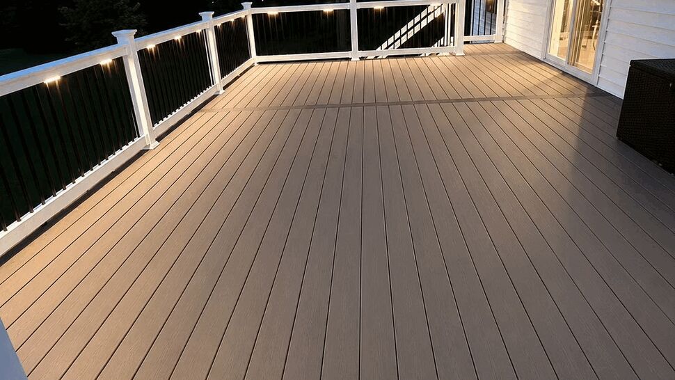 Wide composite deck with lighting | Tycos Roofing And Siding Inc Wide night view of composite deck with white railings and soft lighting