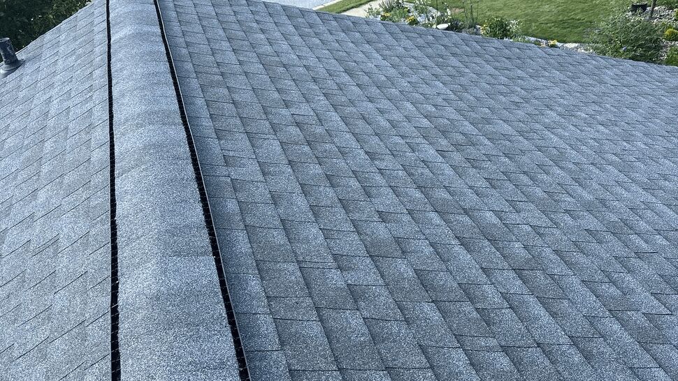 Vented ridge and new shingles | Tycos Roofing And Siding Inc Wide perspective of gray shingled roof ridge and neighborhood street
