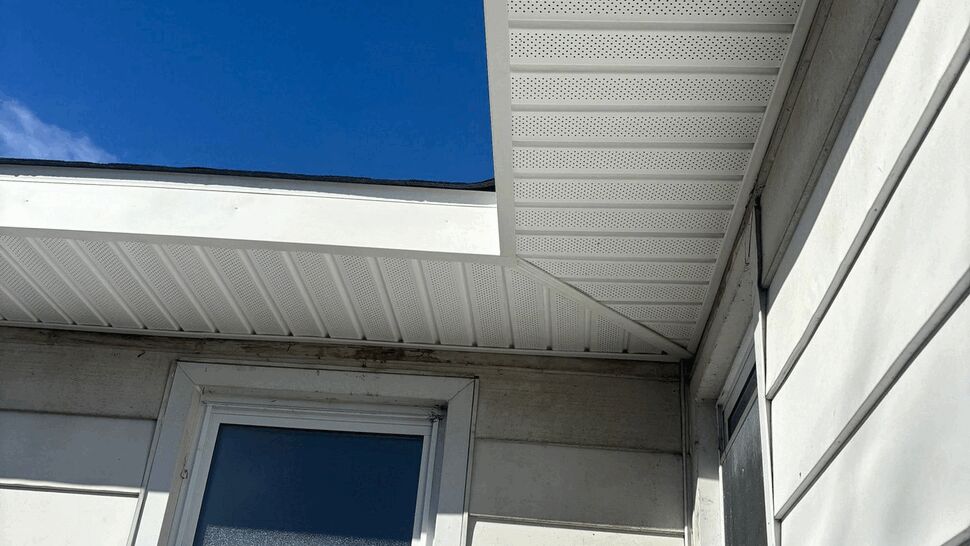 White soffit and window under a clear blue sky