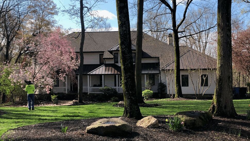 Two-story home among trees with porch and light-colored siding