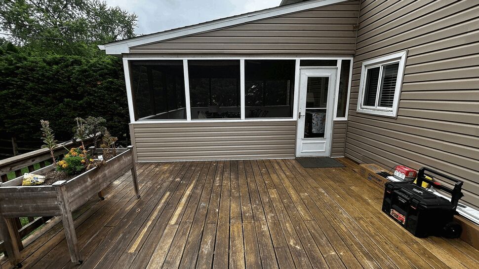 Wide wooden deck leading to a screened porch and door.