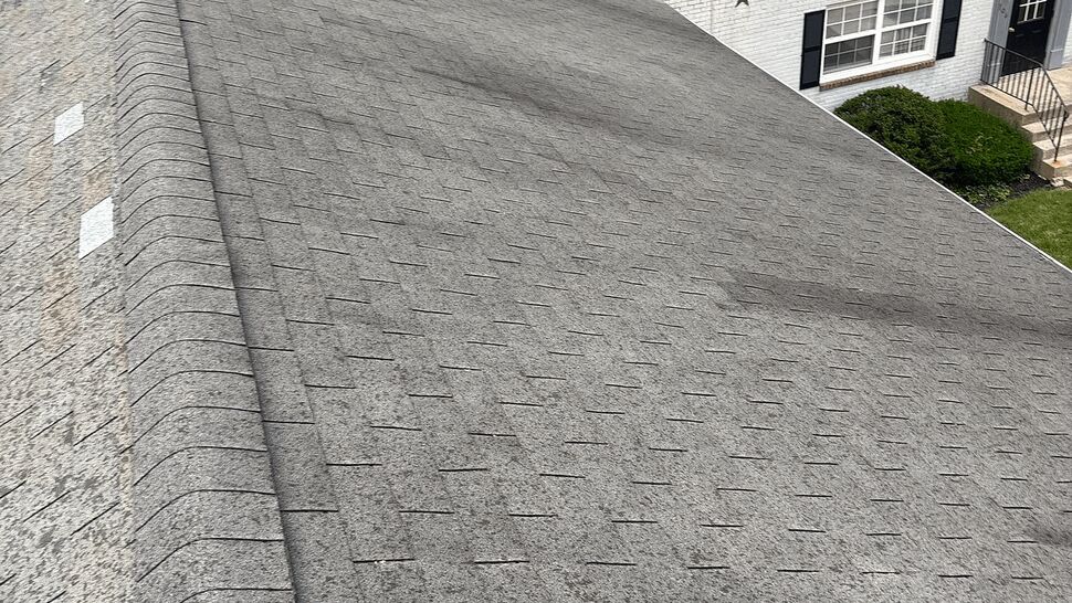 Close-up of aged asphalt shingles and the roof ridge showing wear.