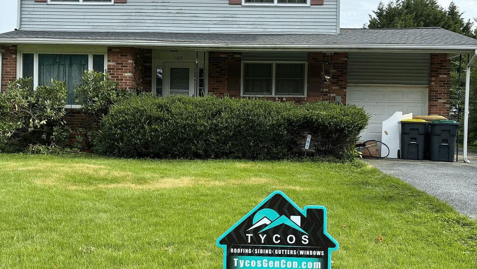 Yard sign on lawn advertising Tycos in front of a two-story house