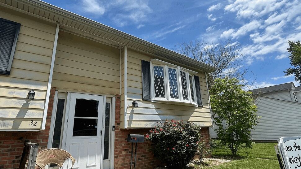 Front entrance with yellow siding, white door, small porch and bay window
