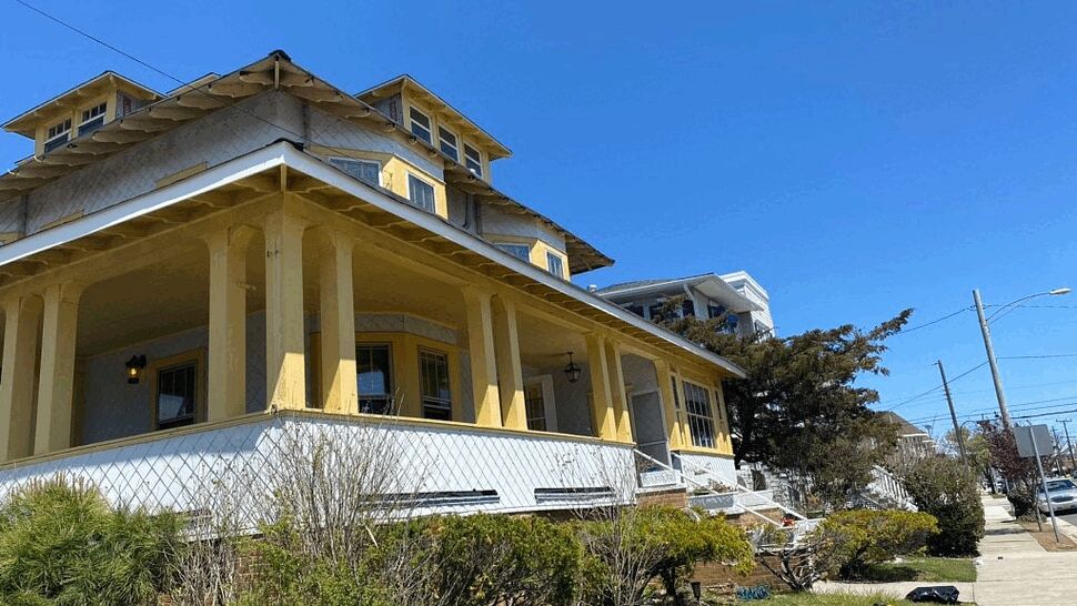 Yellow Victorian house with wraparound porch and exterior siding