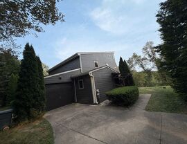 Garage Gutters and Downspouts | Tycos Roofing And Siding Inc Garage side with dark door, white gutters and downspout next to driveway.