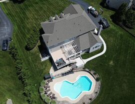 Top-down view of backyard deck, pergola and pool behind a home