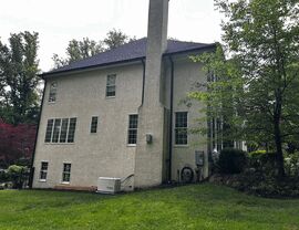 Side elevation of stucco house with chimneys, downspout and generator