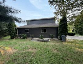 Side Roofline and Exterior Work | Tycos Roofing And Siding Inc Side roofline and dark gray siding with small windows and landscaped yard.