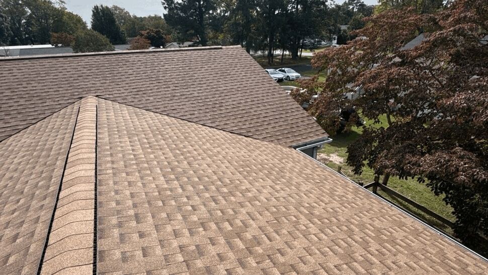 Brown Shingle Roof Overview | Top Roofing & Siding Aerial view of a brown asphalt shingle roof surrounded by trees and homes.
