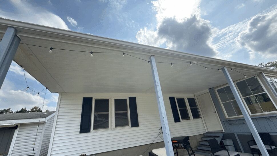 Covered porch with white siding, windows, patio furniture, and string lights