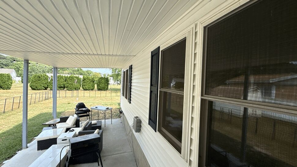 Side porch with white siding, screened windows, outdoor furniture, and lawn view