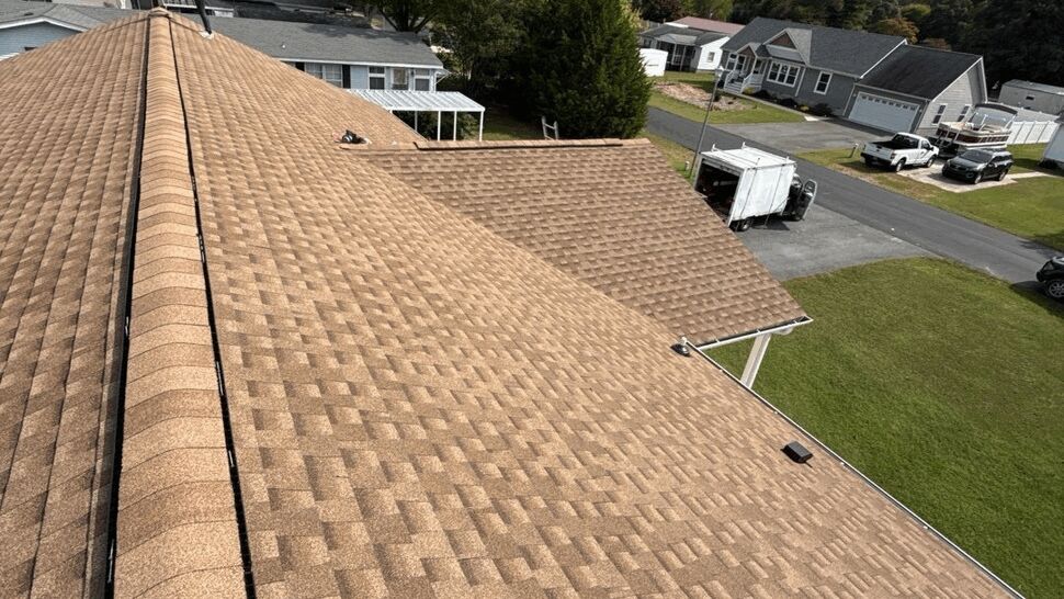 Roof Installation Ridge Line | Top Roofing & Siding Aerial view of brown shingles, roof ridges, and a worker near a home.