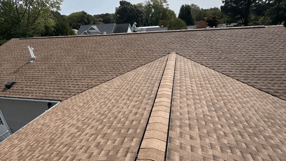 Roof Ridge Shingle Detail | Top Roofing & Siding Close aerial view of brown shingles and a central roof ridge.
