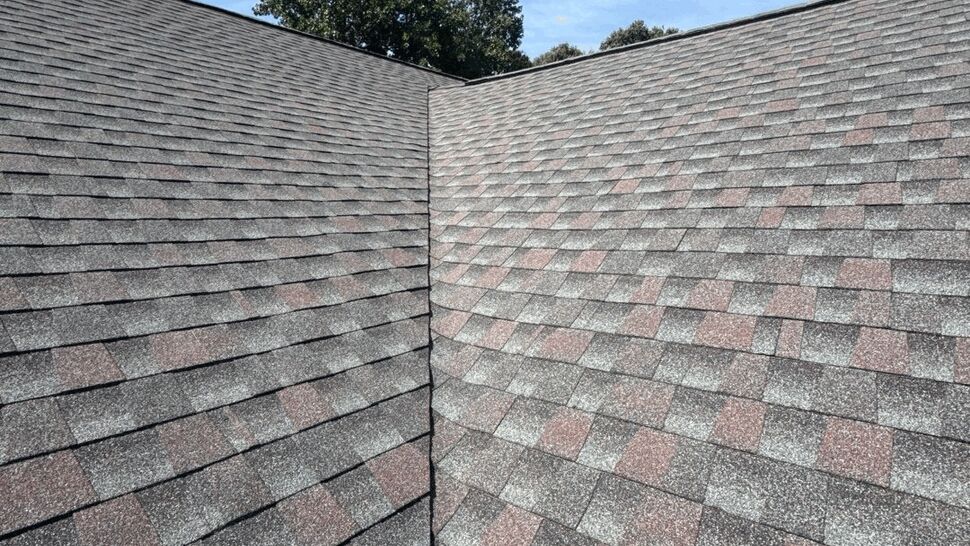 Roof Valley Shingle Detail | Top Roofing & Siding Close view of overlapping gray and red shingles at a roof valley
