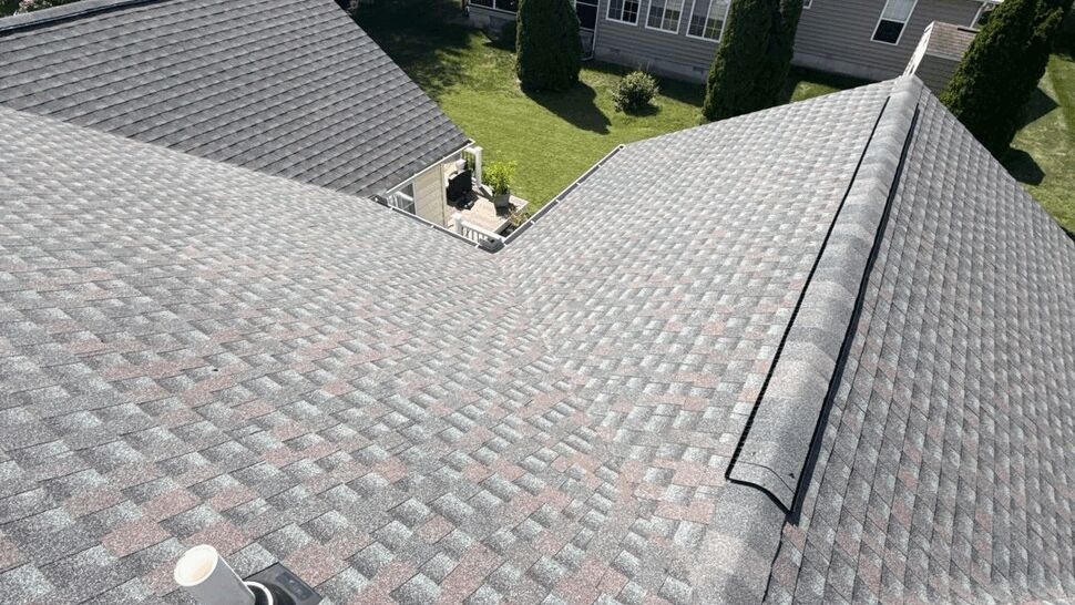 Roof Ventilation and Shingle Detail | Top Roofing & Siding Roof shingles with a visible vent pipe and ridge detail