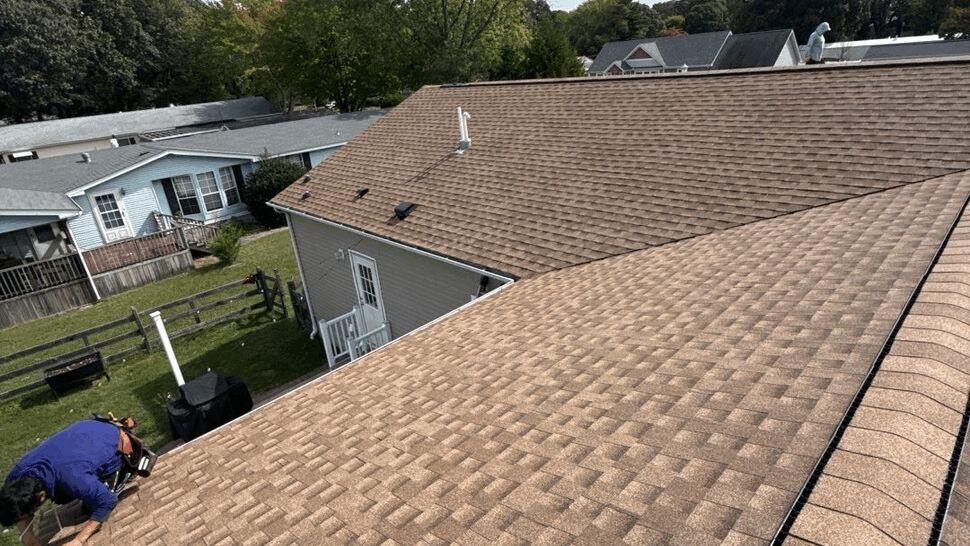 Roofing Worker Inspection | Top Roofing & Siding Roofing professional inspecting brown shingles on a residential roof.