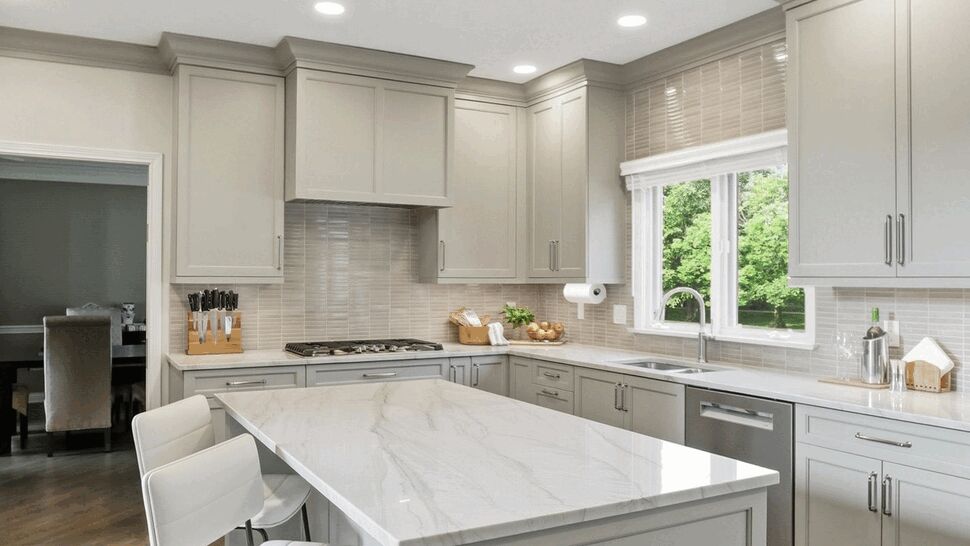 Marble Island with Gray Cabinets | ACo Flooring, Cabinets, Kitchens & Baths Modern gray kitchen with large marble island and white bar chairs