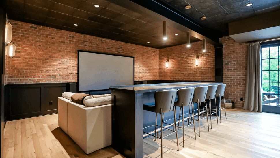 Entertainment bar with stools and a sofa facing a screen.