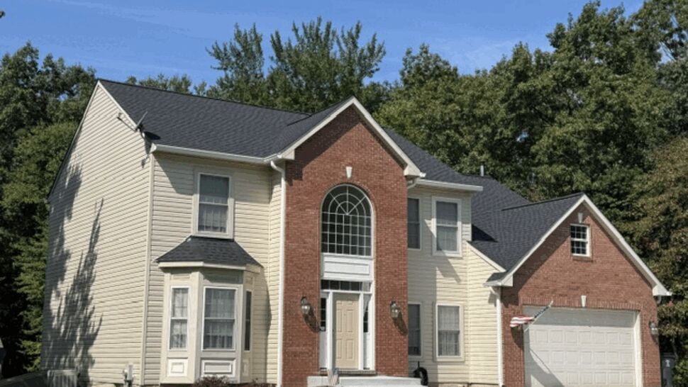 Angled side view of house showing dark roof and cream vinyl siding