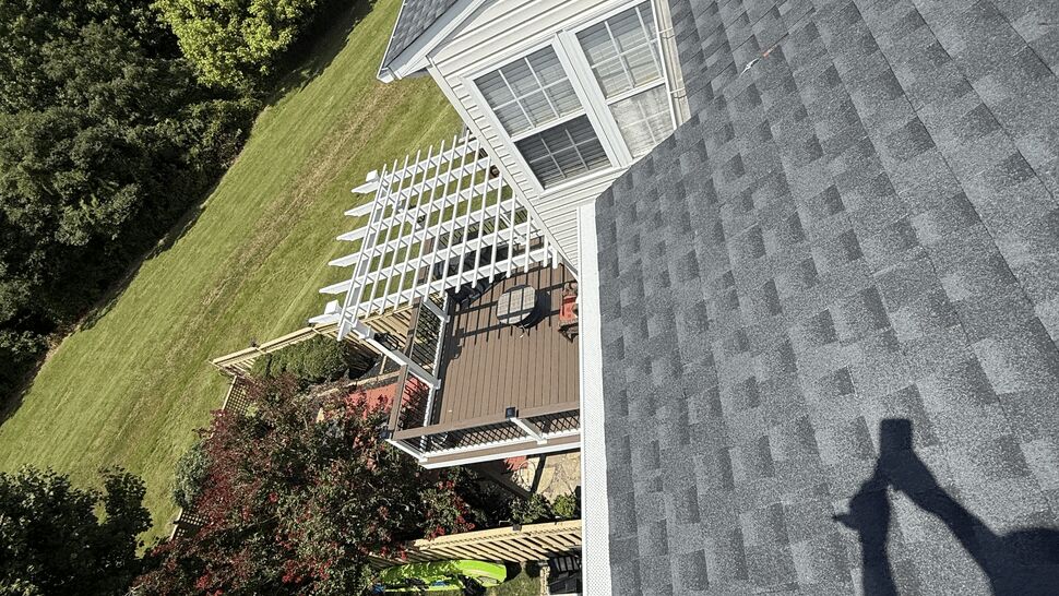 Aerial view of gray shingled roof over backyard deck and pergola.