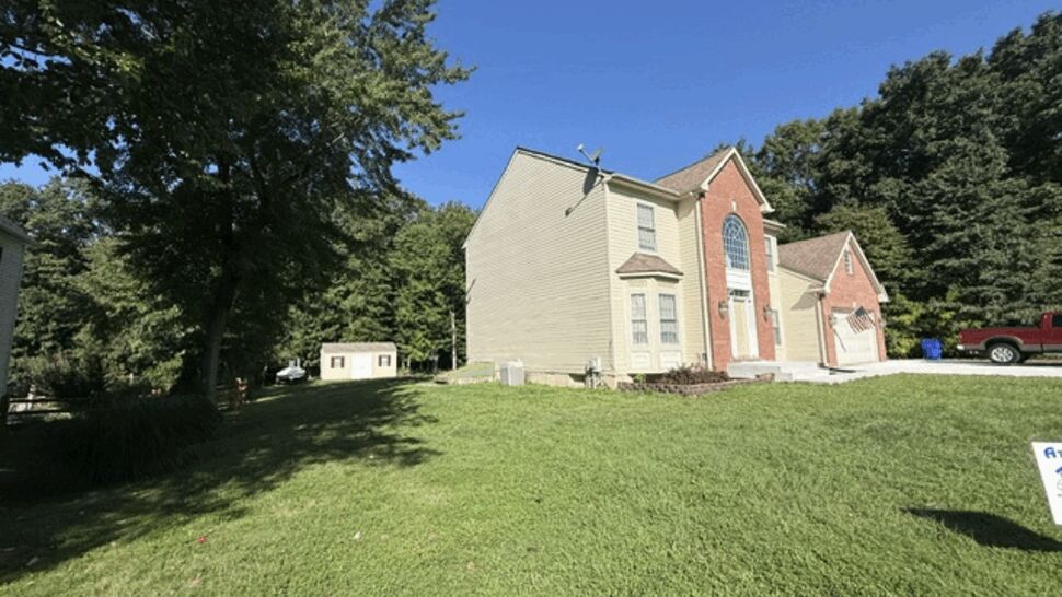 Angled side view of house showing driveway, lawn, and mixed brick and siding exterior