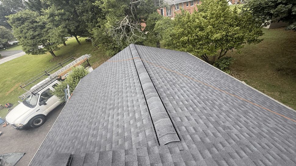 Top-down view of an asphalt shingle roof with a work truck nearby.